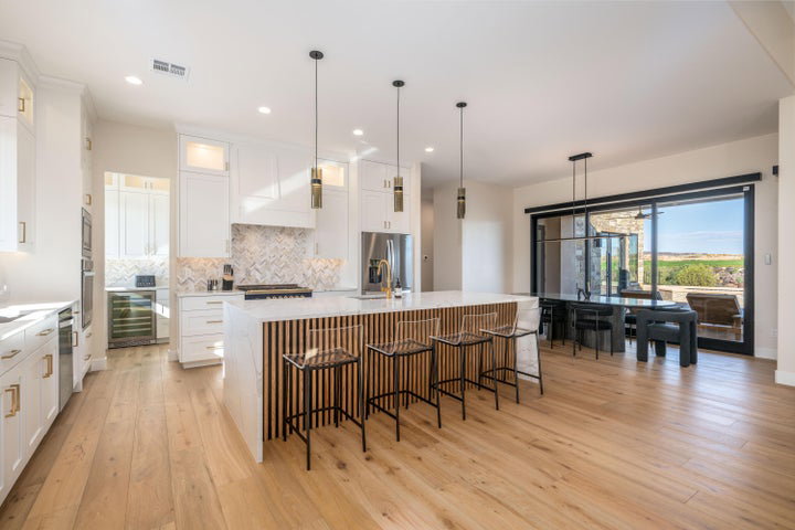 Kitchen with an island with sink, light wood-type flooring, backsplash, a kitchen breakfast bar, and wine cooler