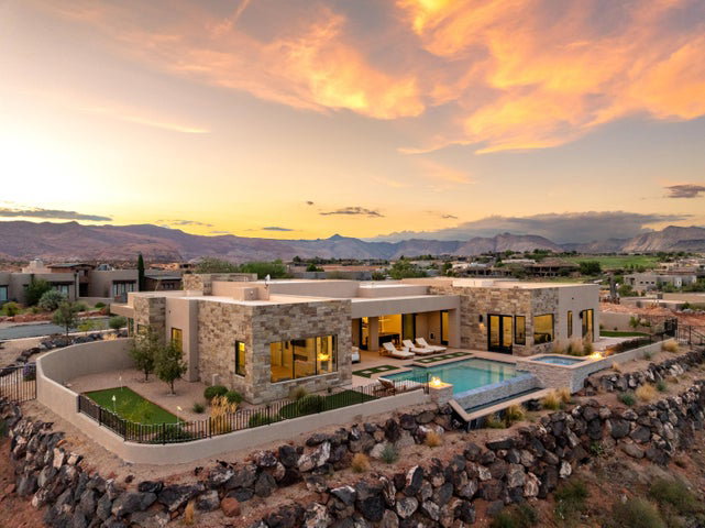 Rear view of house with a patio area, stone siding, a mountain view, and a pool with connected hot tub