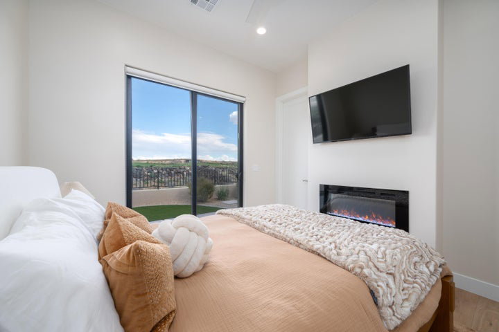 Bedroom with access to exterior, a glass covered fireplace, and recessed lighting