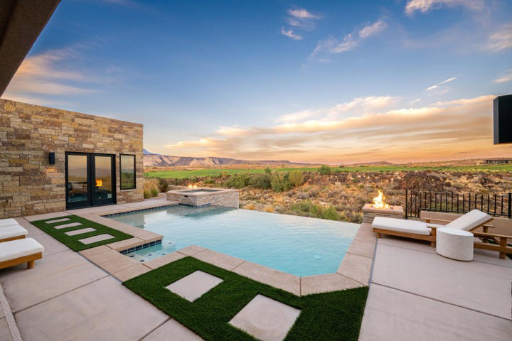 Pool at dusk featuring a mountain view, a pool with connected hot tub, and a patio