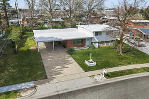 4-level home featuring a front lawn, a carport, concrete driveway, brick siding, and a residential view