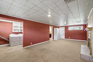 Below grade area with light colored carpet, washer and dryer, and a fireplace with flush hearth