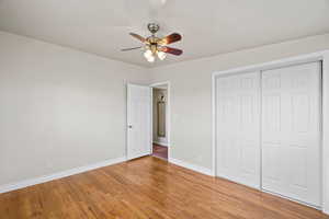 Unfurnished bedroom with light wood-style floors, ceiling fan, and a closet