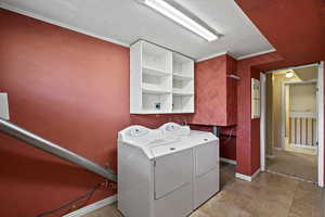 Laundry area with crown molding, a textured ceiling, and washer and clothes dryer
