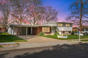 4-level home with a front yard, a carport, concrete driveway, and brick siding