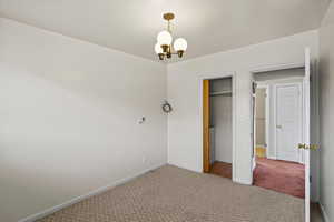 Unfurnished bedroom featuring carpet floors, a closet, and hanging lights