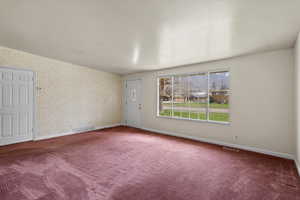 Carpeted empty room featuring baseboards and wallpapered walls