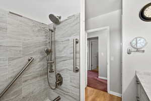 Bathroom featuring vanity, tiled shower, and light wood-style flooring