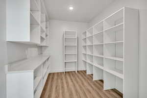 Walk in closet with light wood finished floors