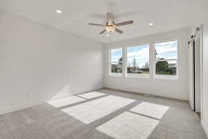 Spare room featuring light carpet, ceiling fan, and recessed lighting