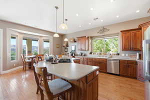 Kitchen featuring wood finish cabinetry, a kitchen bar, a center island, light wood-style floors, and light countertops