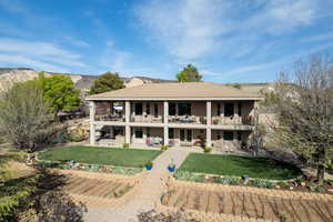 Rear view of property featuring a lawn, a balcony, and a mountain view