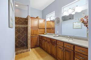 Bathroom featuring double vanity and tiled shower