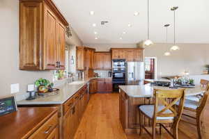 Kitchen featuring wood finish cabinets, black appliances, light wood-type flooring, a breakfast bar, and decorative light fixtures