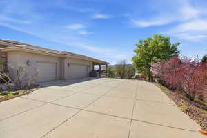 View of side of property with stucco siding, an attached garage, and concrete driveway