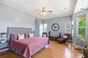 Bedroom featuring hardwood / wood-style flooring, arched walkways, and ceiling fan