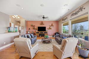 Living area with light wood-style flooring, a ceiling fan, and hanging lights
