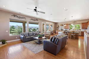 Living room with light wood-style floors, a ceiling fan, and recessed lighting