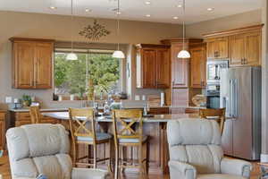 Kitchen with wood finish cabinetry, stainless steel appliances, light wood-style flooring, and a breakfast bar