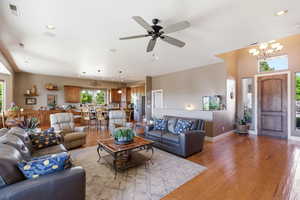 Living room featuring light wood-style flooring, hanging lights, and a ceiling fan