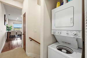 Laundry area with stacked washer and clothes dryer, carpet floors, and recessed lighting