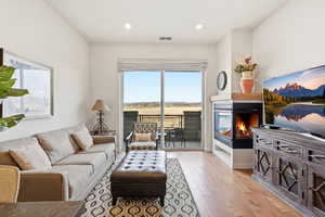 Living room with light wood-style floors, a multi sided fireplace, and recessed lighting