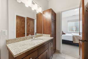 Ensuite bathroom featuring vanity, light carpet, and light tile patterned floors