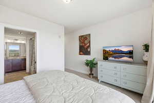 Bedroom with ensuite bathroom and light colored carpet