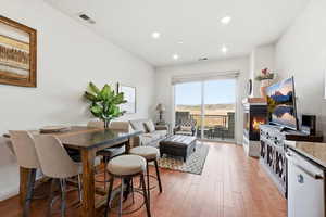 Dining room with light wood-style floors, a warm lit fireplace, and recessed lighting