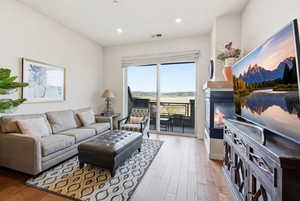 Living area with light wood-style floors, recessed lighting, and a glass covered fireplace