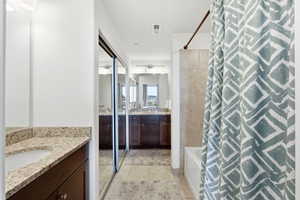 Full bathroom with two vanities, shower / bath combination with curtain, and light tile patterned floors