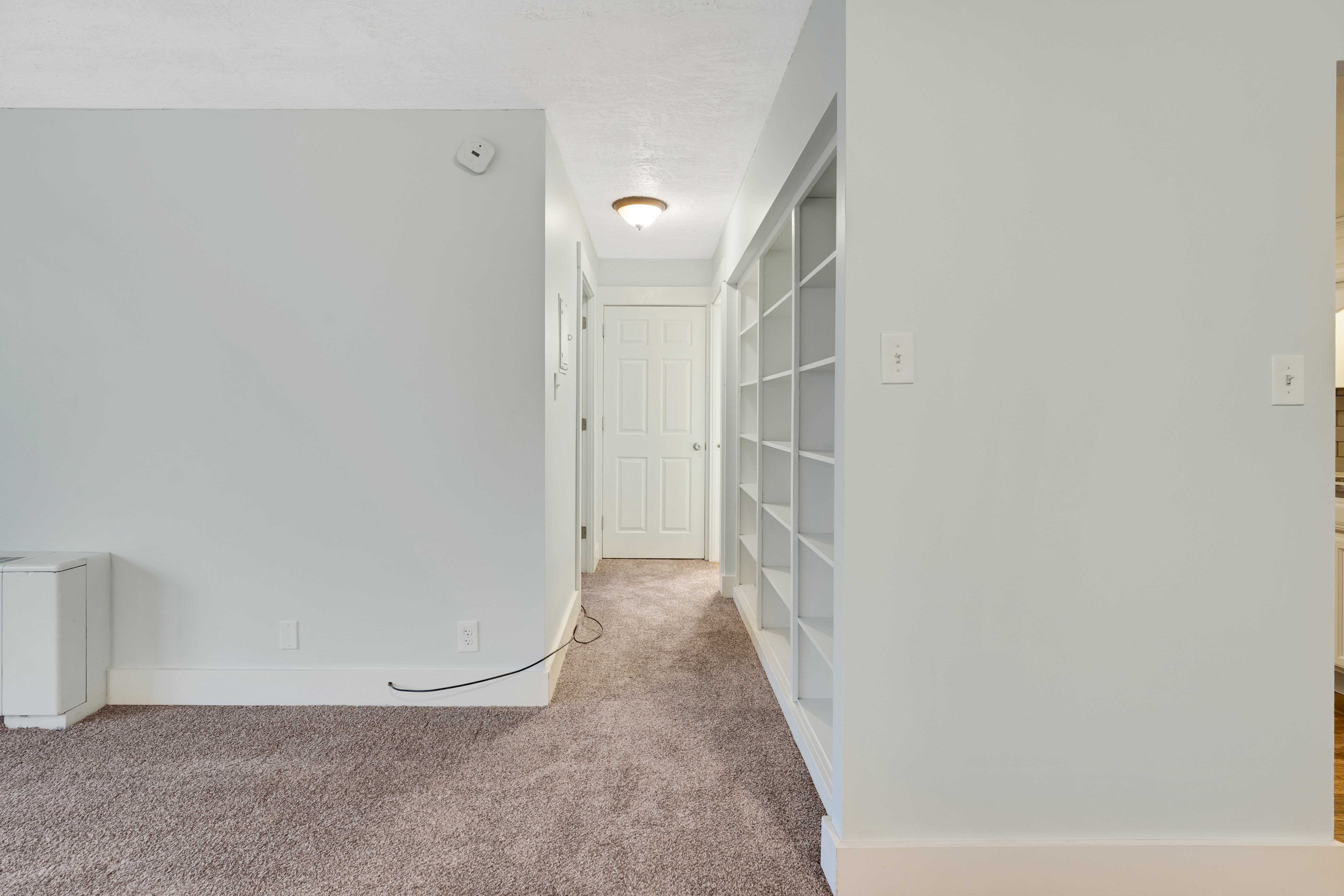 Hall featuring light carpet and baseboards