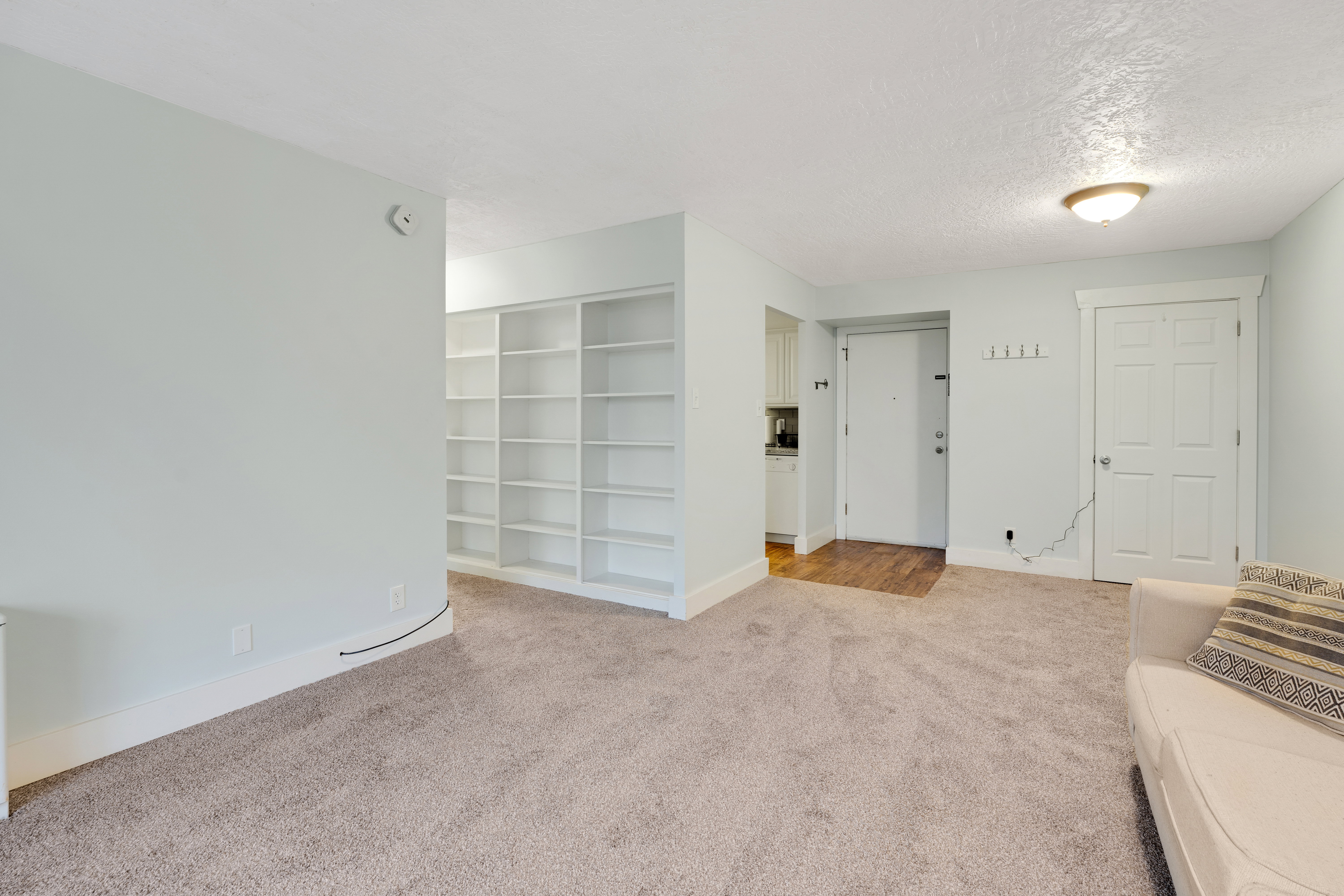 Unfurnished living room with light carpet and a textured ceiling