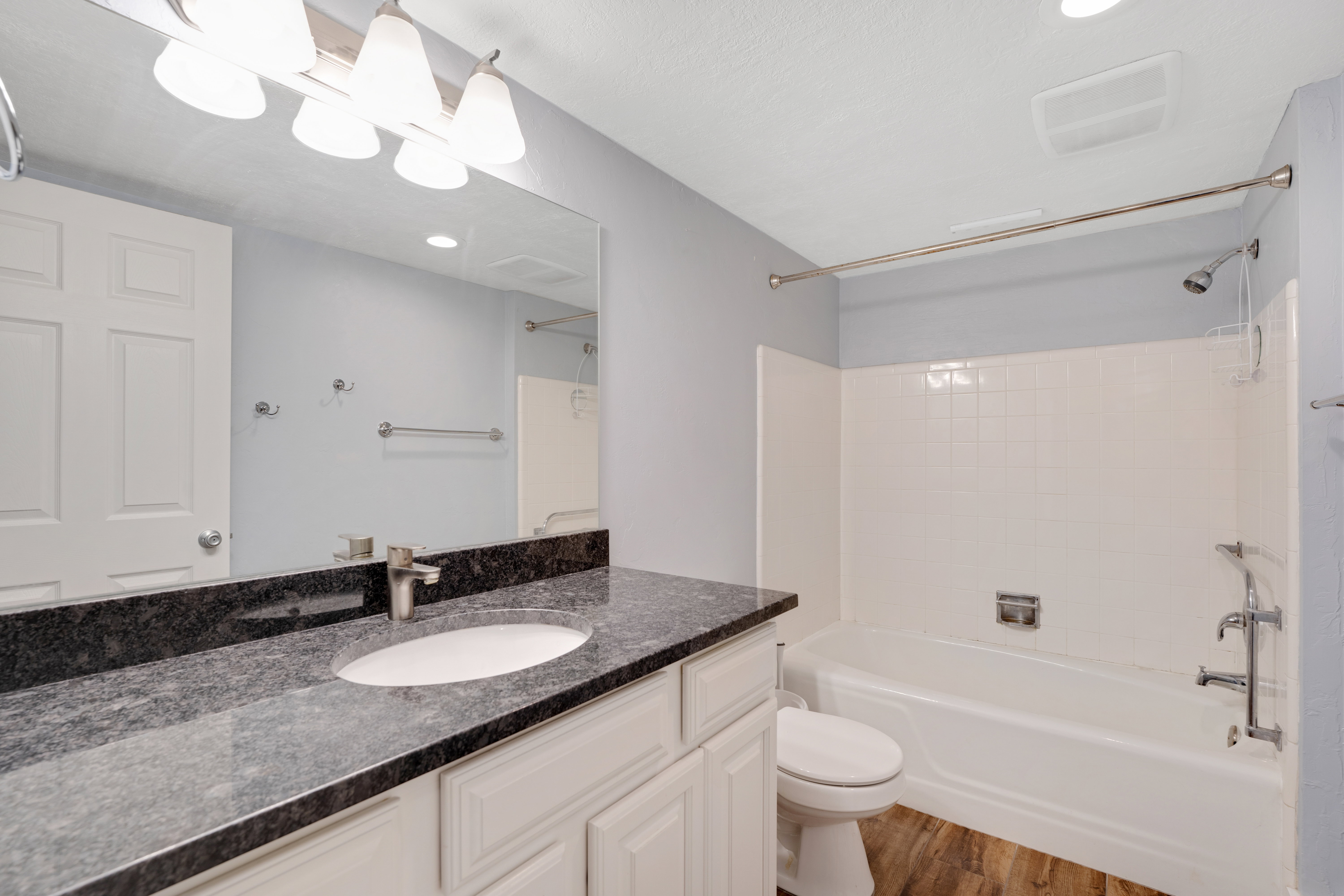 Bathroom with vanity, wood finished floors, and bathing tub / shower combination