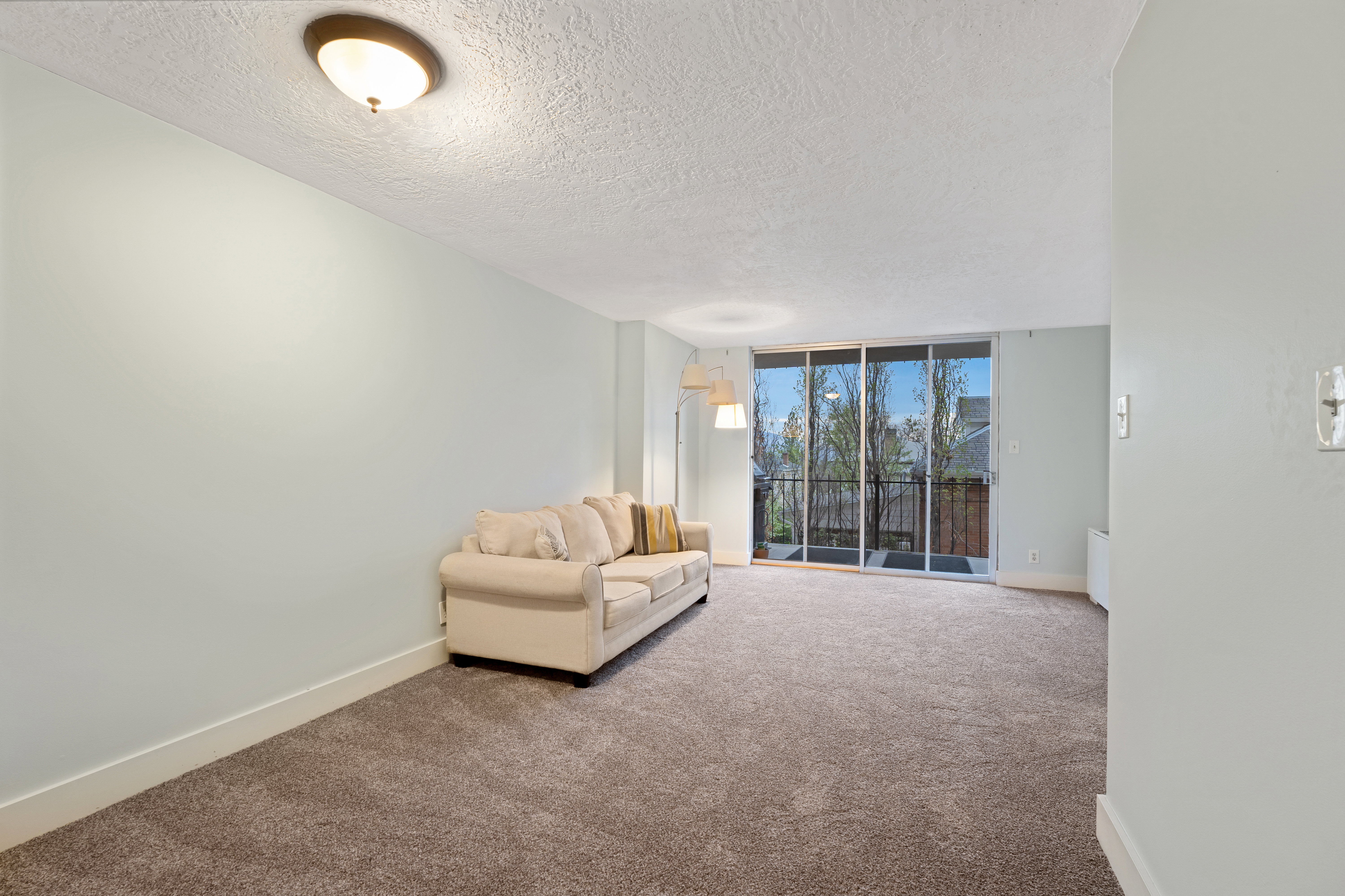 Living area with expansive windows, carpet, and a textured ceiling