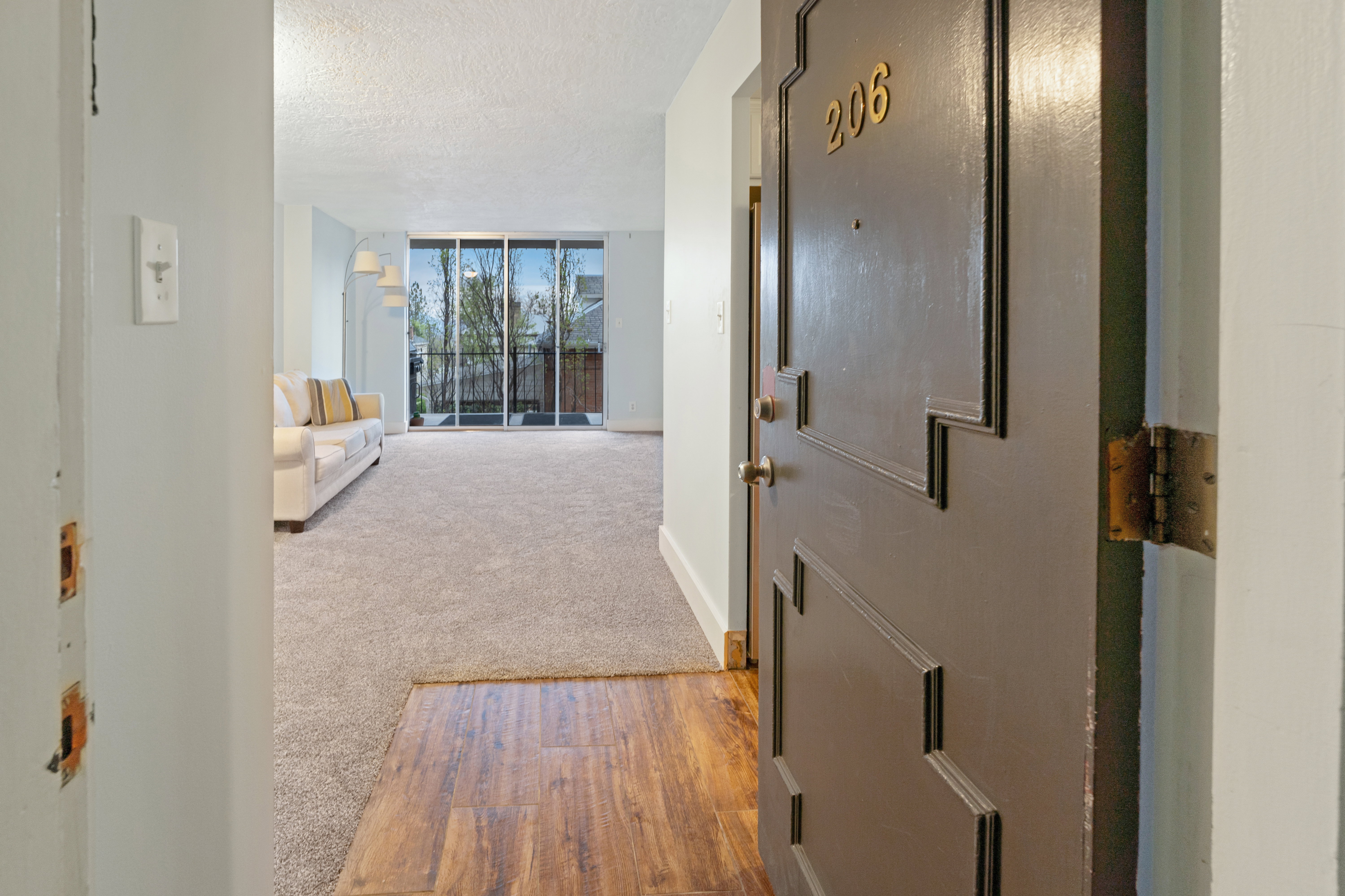 Hallway with a textured ceiling, light wood-style floors, and light colored carpet