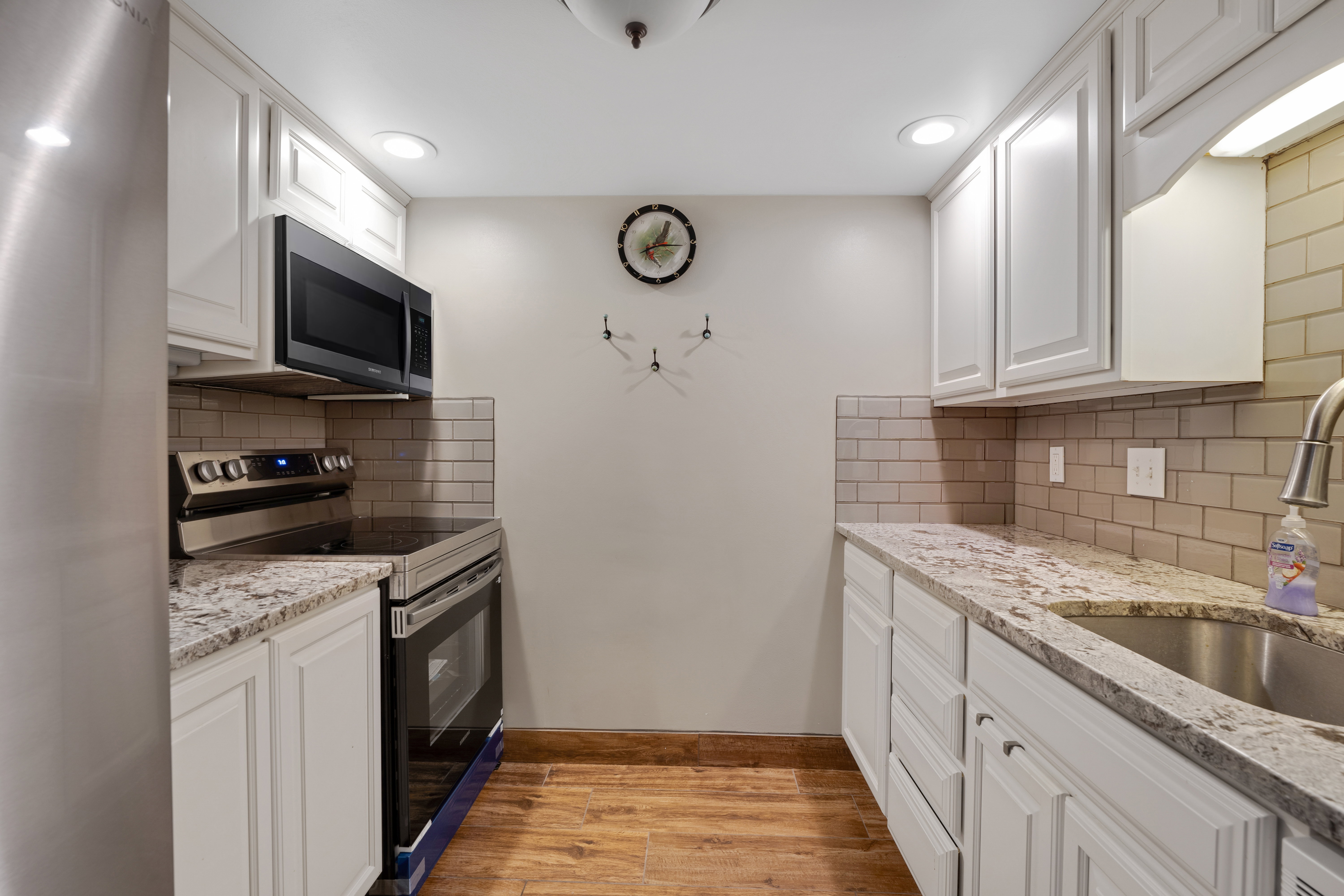 Kitchen featuring stainless steel appliances, light stone counters, light wood-type flooring, white cabinets, and recessed lighting
