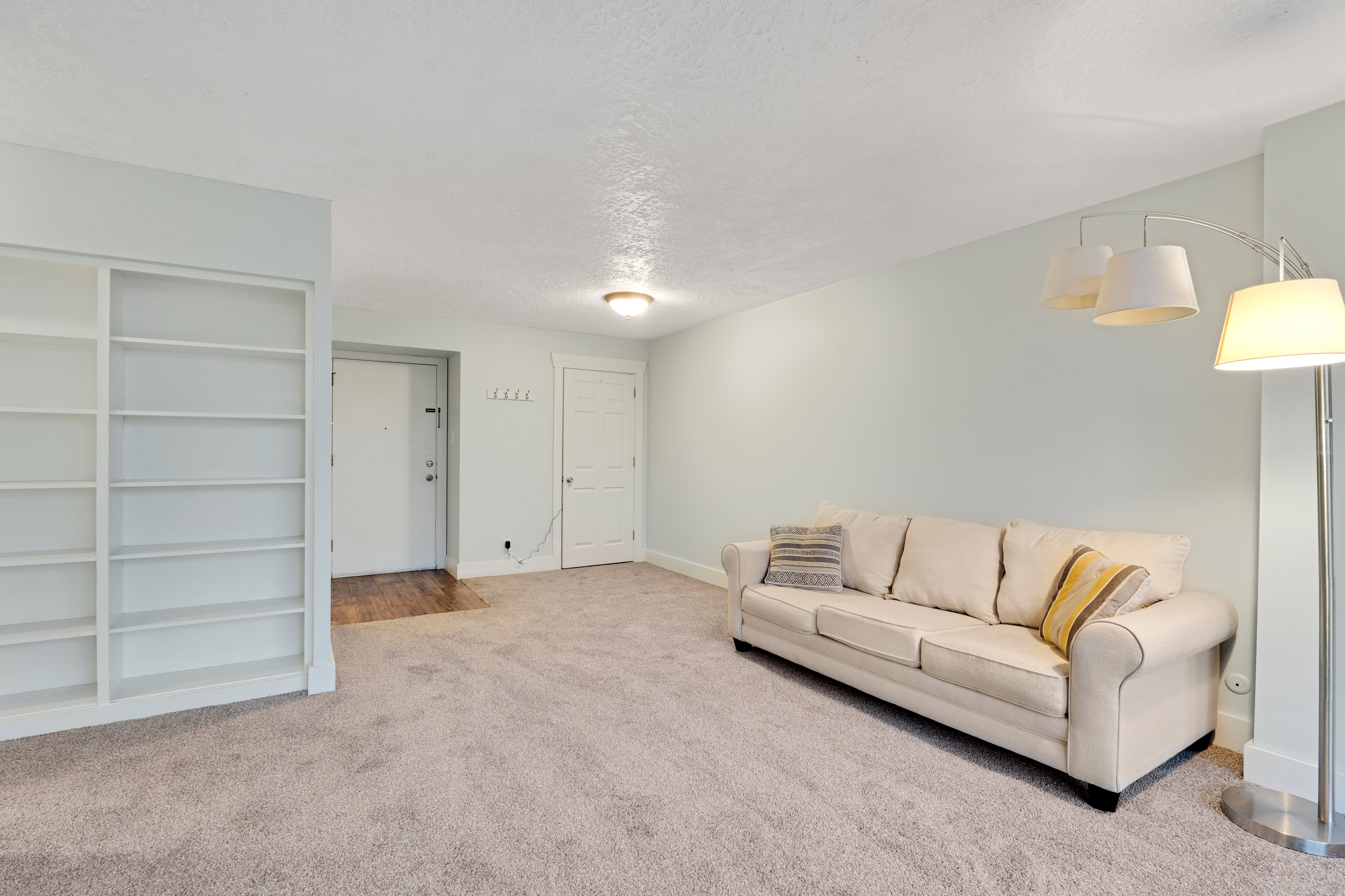 Carpeted living area featuring a textured ceiling and baseboards