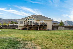 Back of house featuring a deck with mountain view, a fenced backyard, and roof with shingles