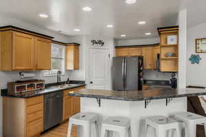 Kitchen with a breakfast bar, open shelves, a peninsula, stainless steel appliances, and light wood-type flooring
