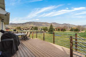 Deck with area for grilling, a mountain view, outdoor dining space, a residential view, and a lawn