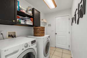 Laundry area with cabinet space, washer and dryer, and light tile patterned floors