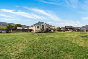 Rear view of house with a deck with mountain view and a fenced backyard