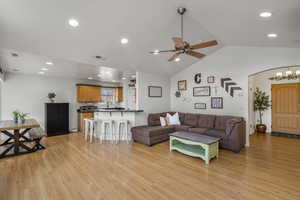 Living area with recessed lighting, light wood finished floors, arched walkways, vaulted ceiling, and ceiling fan