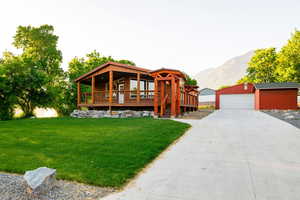 View of front facade featuring an outdoor structure, a detached garage, a front lawn, and a mountain view