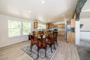Dining area with lofted ceiling, light wood finished floors, and recessed lighting