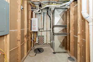 Utilities featuring heating unit, tankless water heater, and electric panel