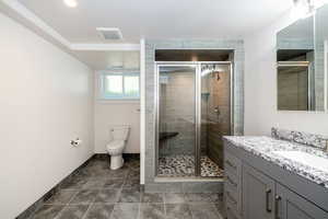 Full bathroom with vanity, a stall shower, and dark tile patterned flooring