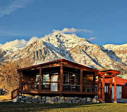 Back of house with a garage, a deck with mountain view, and a sunroom