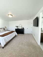 Bedroom with a textured ceiling, light carpet, and ensuite bath